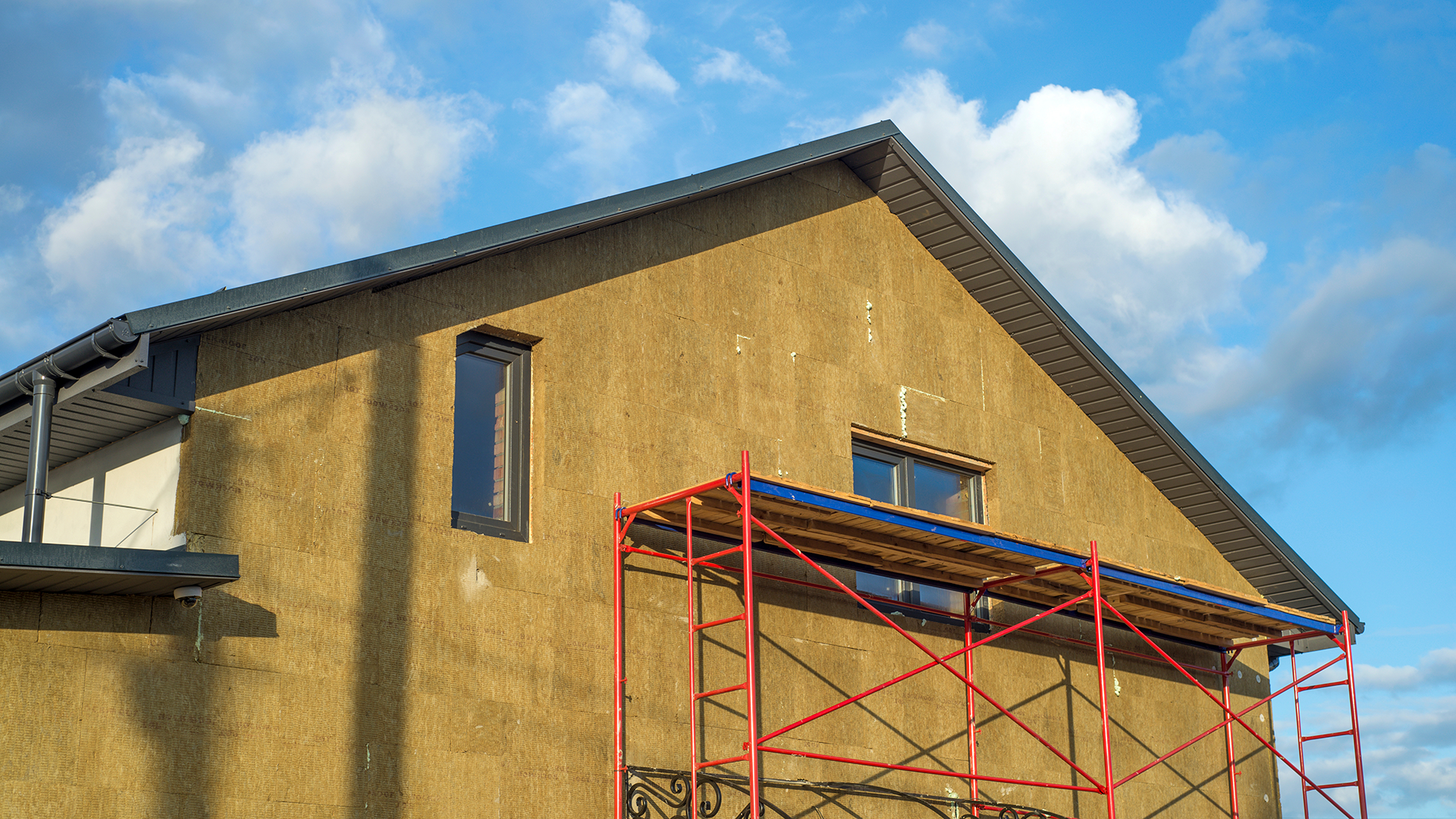 EIFS installation showing the application of continuous mineral wool insulation boards creating a seamless thermal envelope around the entire structure, eliminating weak spots and thermal bridges that compromise energy efficiency.